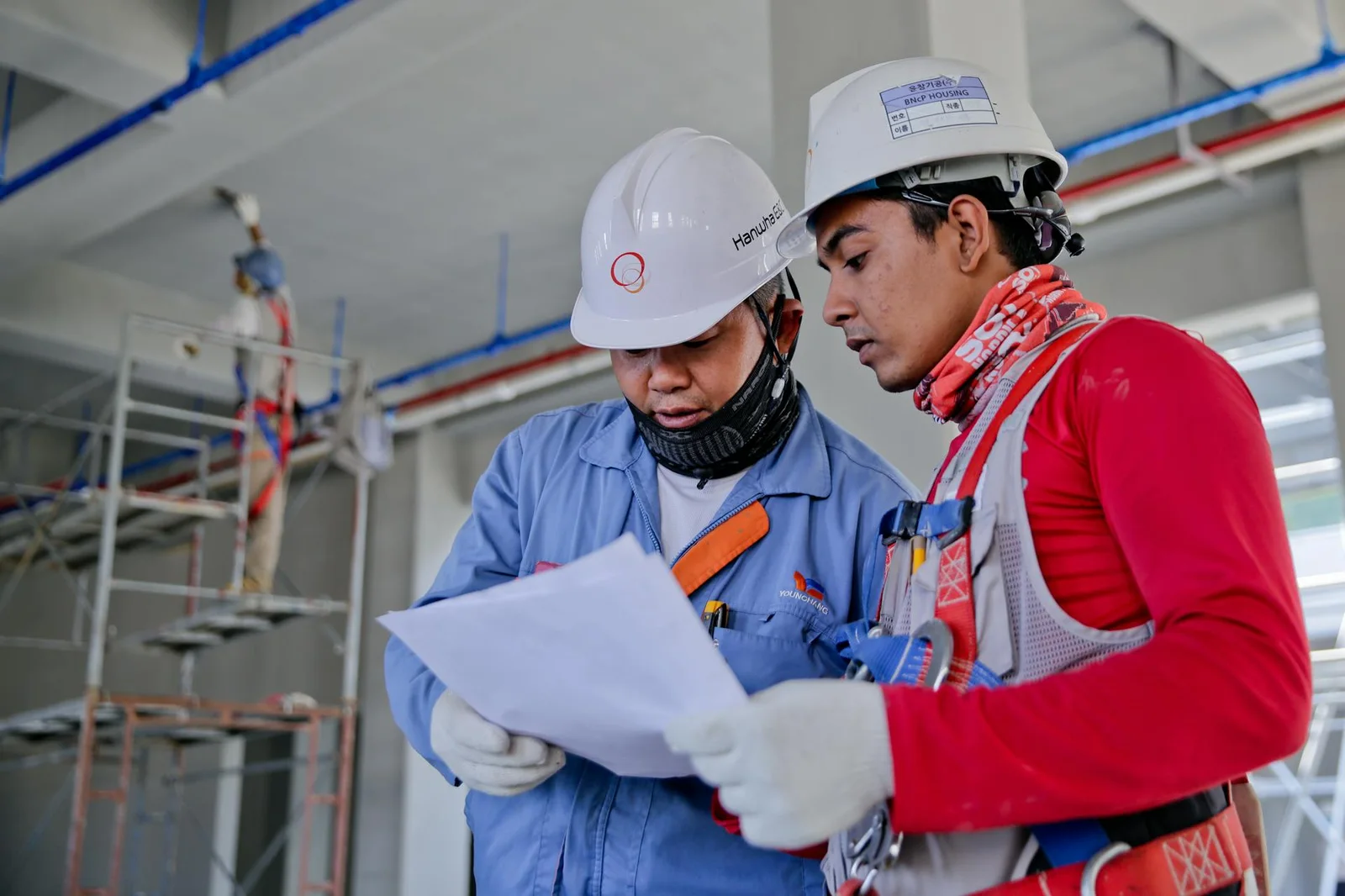 Two ICEng engineers in hard hats reviewing drawings on a construction site
